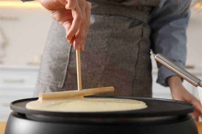 woman-cooking-delicious-crepe-electrical-pancake-maker-kitchen-closeup